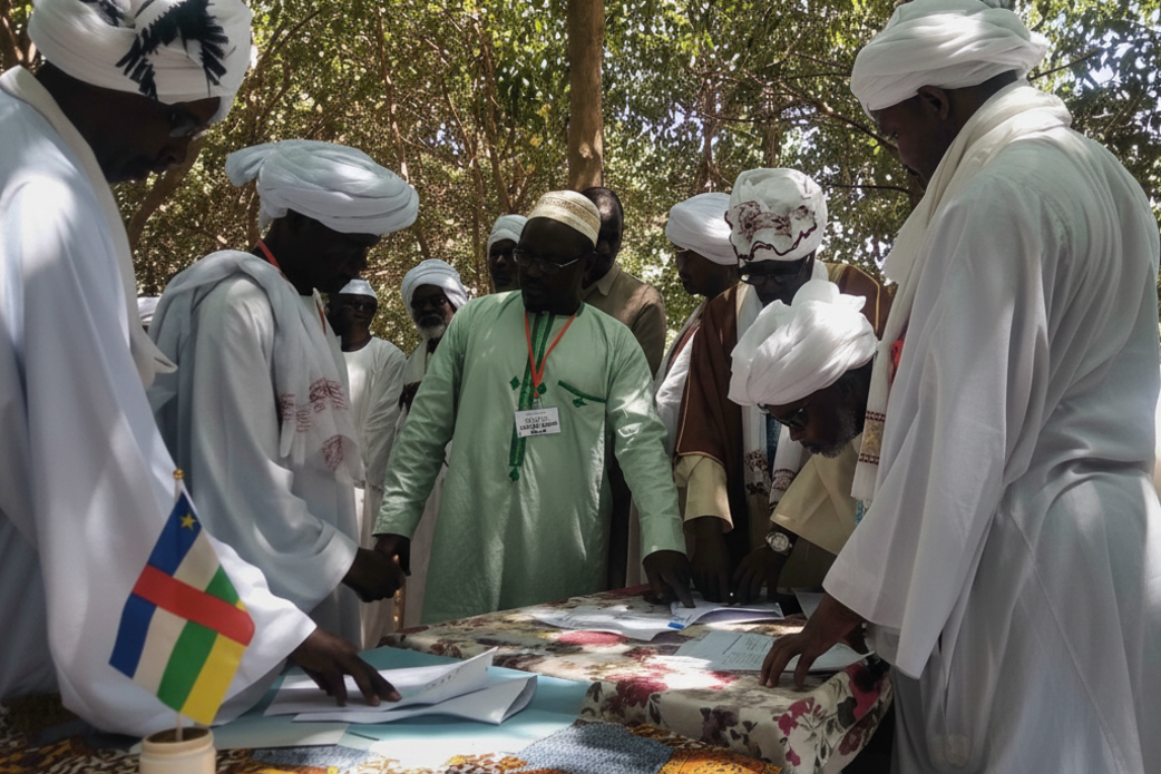 A group of people stand around a table, on which there is a Central African flag displayed