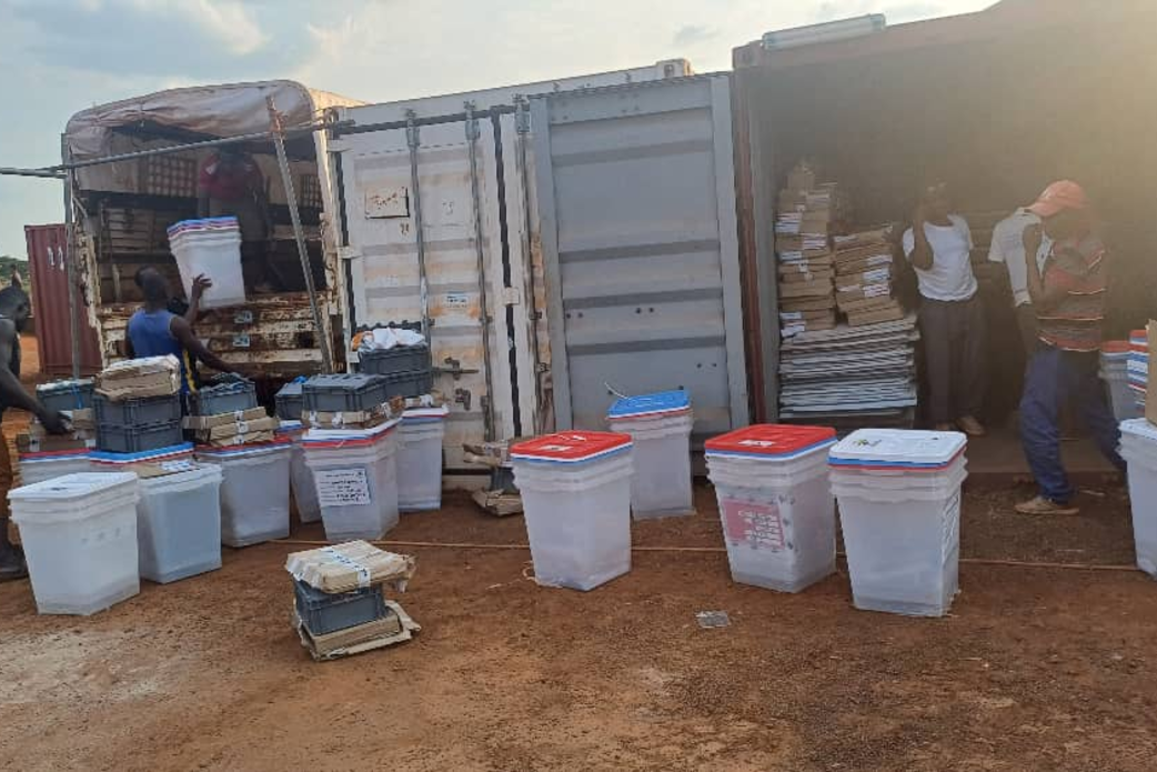 Un groupe de personnes manipule des cartons contenant du matériel électoral.