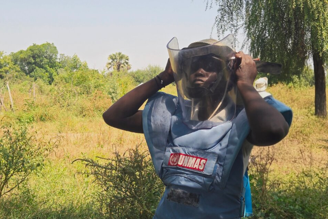 a woman deminer is putting on a protective mask